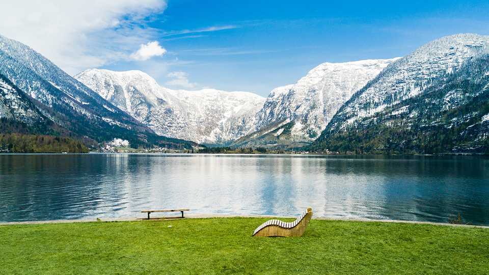 Sob a grama, vê-se um lago de água límpida e uma montanha congelada ao fundo